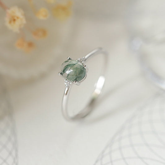 An S925 silver ring with a green moss agate centerpiece, presented on a white background with floral accents.